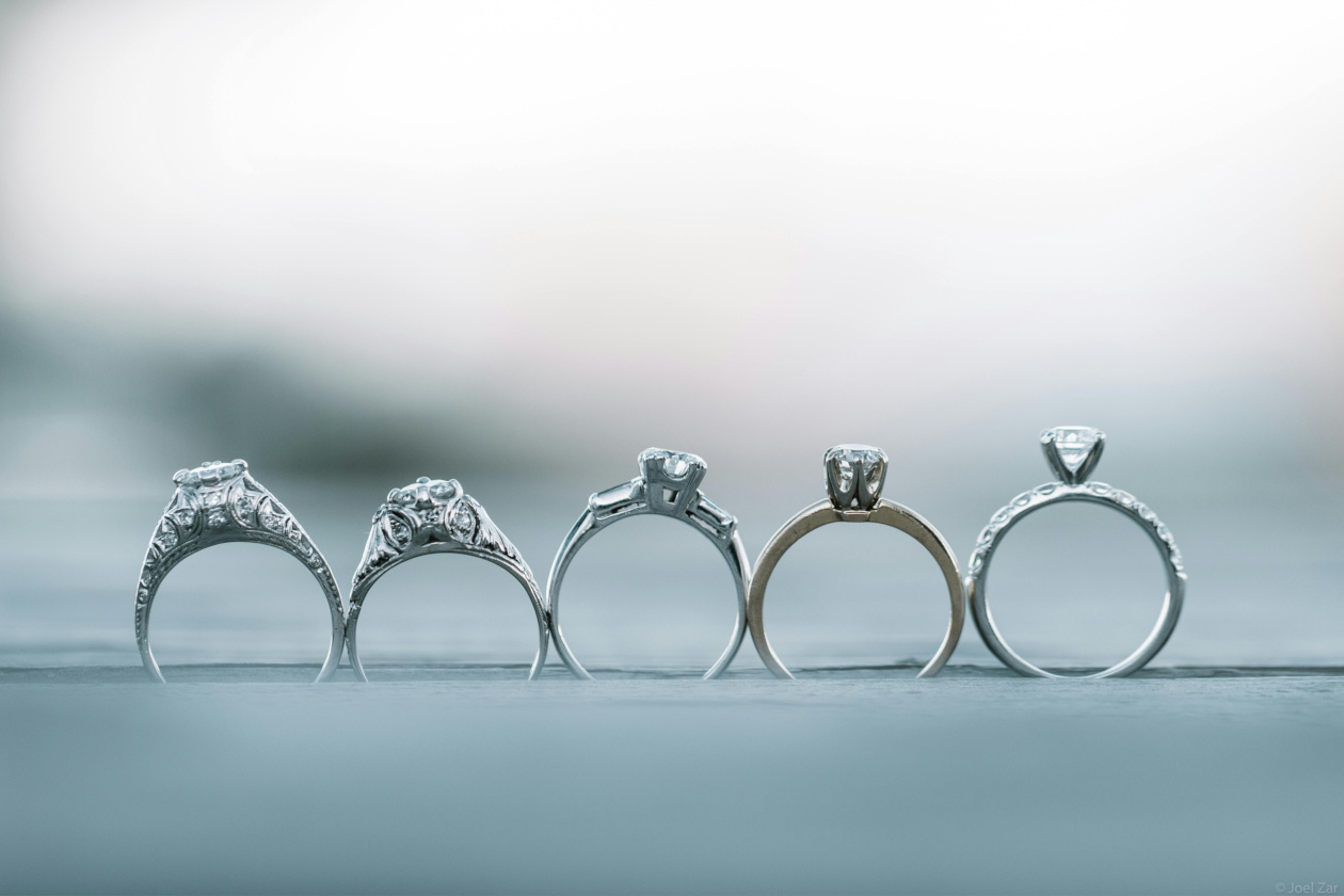 Five unique rings sitting in a line overlooking a blurred landscape