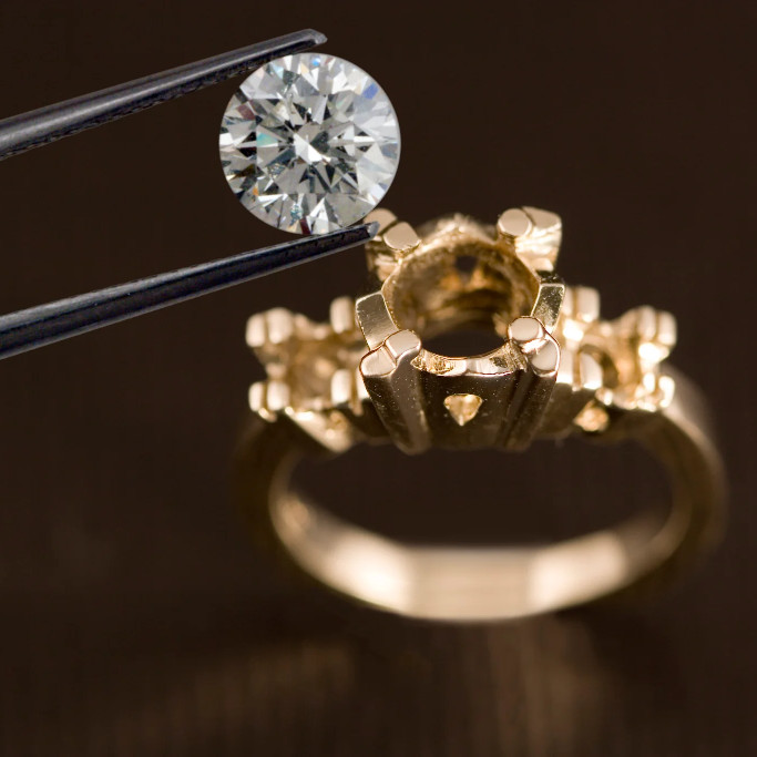 A diamond being carefully placed into a ring